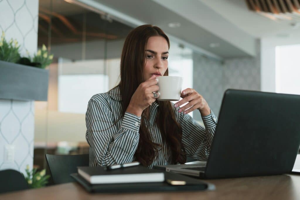 mujer tomando taza de cafe con laptop o computadora en Office Seat